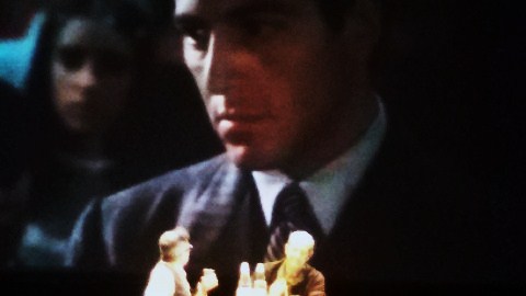 Marcello Fois e Roberto Costantini sotto lo schermo di un cinema che proietta una scena de Il Padrino