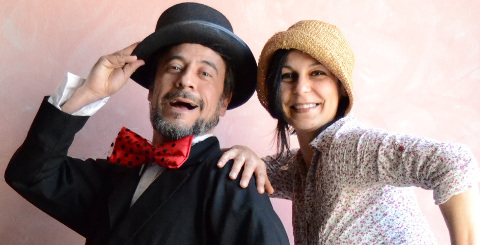 un uomo con papillon rosso e cappello nero accanto a una donna con un cappello di paglia