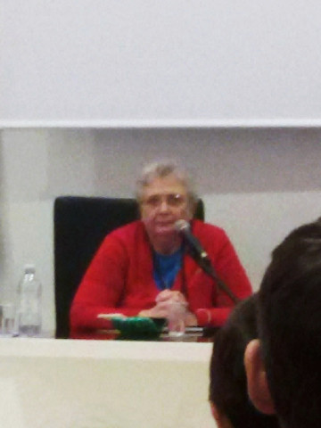 Agnese Moro seduta a un tavolo davanti a un microfono