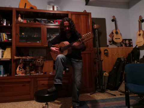Francesco Loccisano mentre suona una chitarra con un piede poggiato su uno sgabello